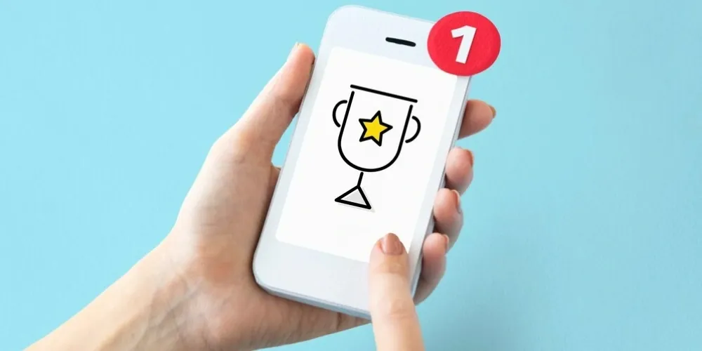 Hand holding a phone showing a trophy reward notification